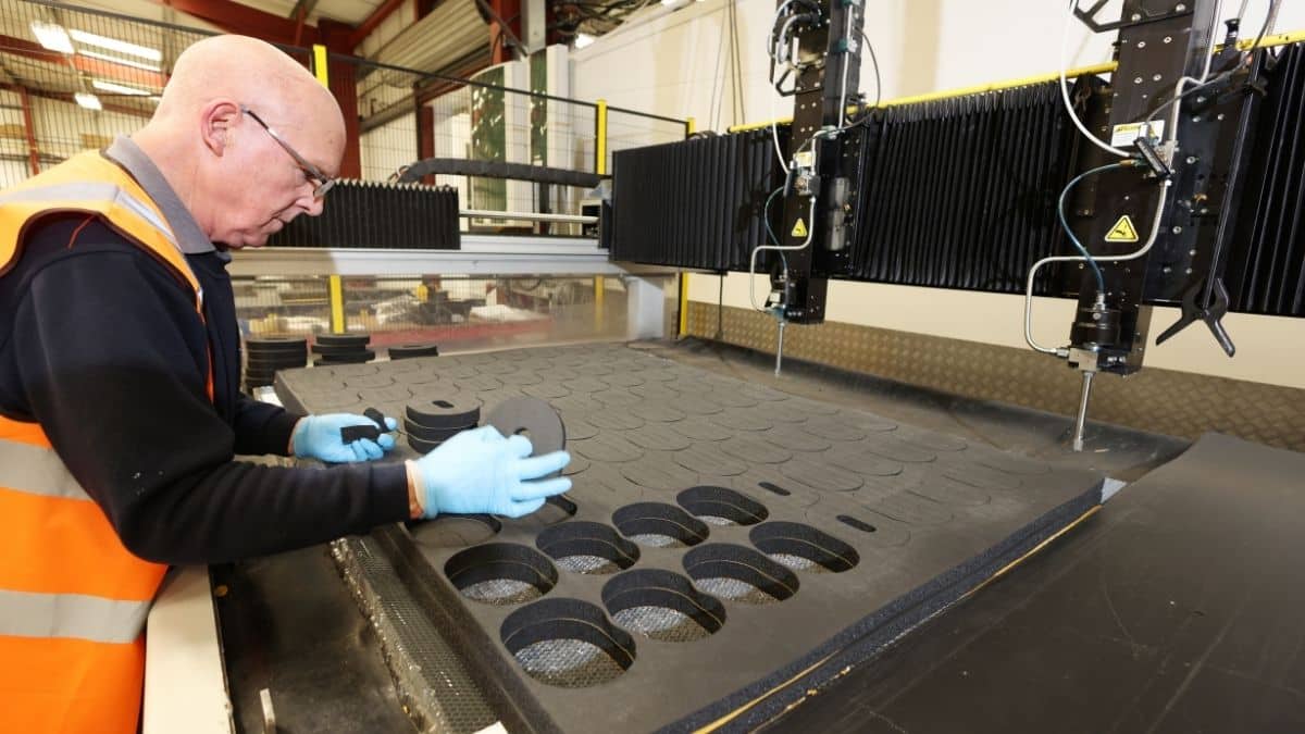 A man in orange hi viz removes foam parts cut on a twin water jet cutter